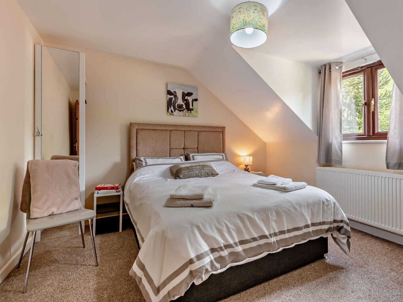 Une chambre à coucher avec un lit, une table de chevet, une lampe, une fenêtre et une porte.