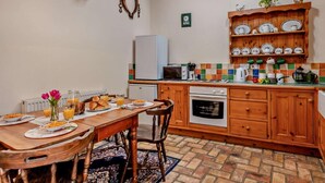 A cozy kitchen with wooden cabinets, a tiled backsplash, and a dining area with a table set for breakfast. - 2 Bed in King's Lynn (oc-77764) (Tattersett)