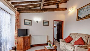 A cozy living room with a sofa, a television on a wooden cabinet, a small table with a rug, and a radiator. - 2 Bed in King's Lynn (oc-77764) (Tattersett)