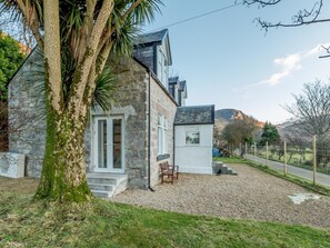A stone house with a gravel driveway, a wooden bench, and a view of the countryside. - 4 Bed in Isle Of Arran (oc-77791) (Lochranza)