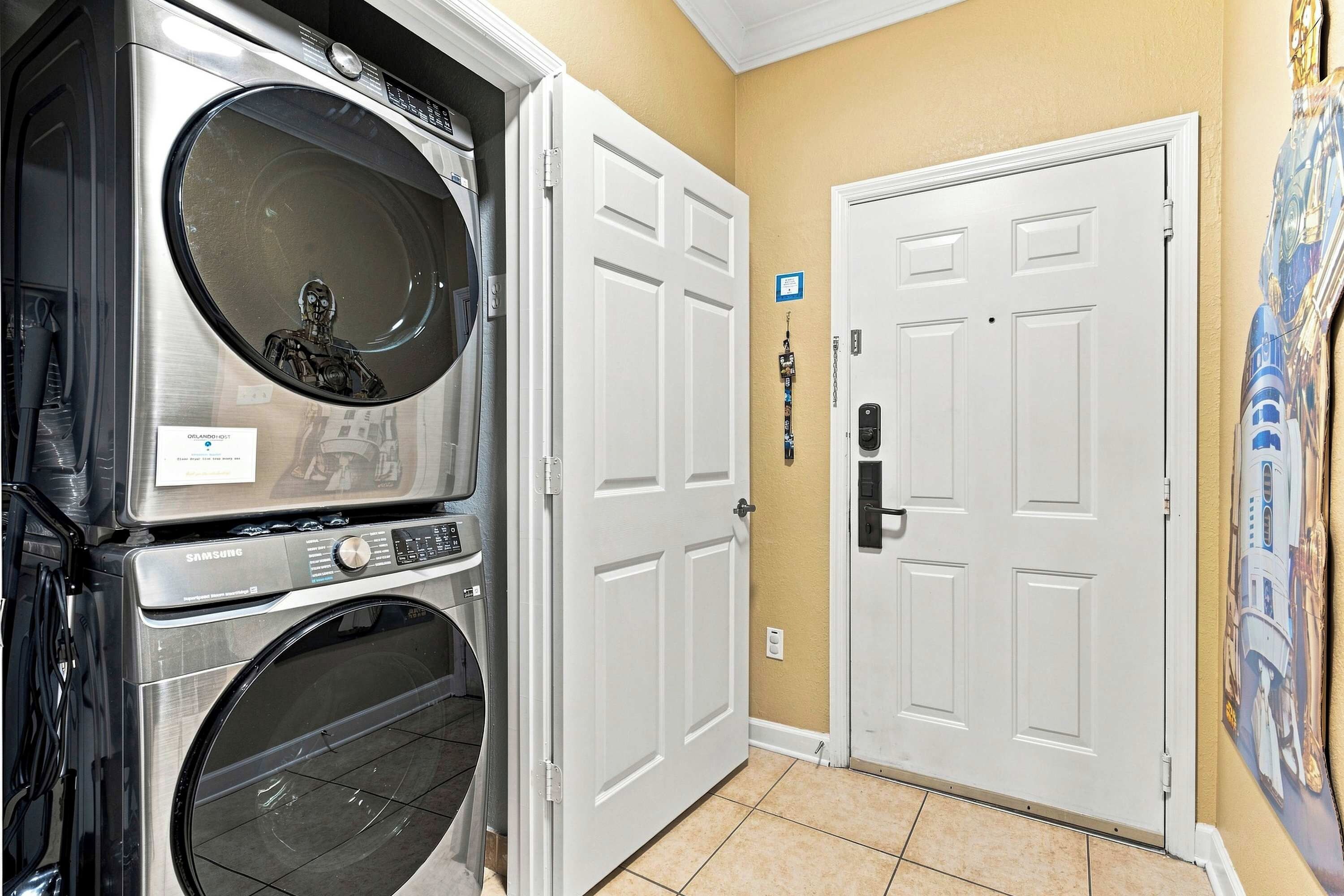 A laundry room with stacked washers and dryers, a door with a keycard lock, and a wall with a Star Wars mural.
