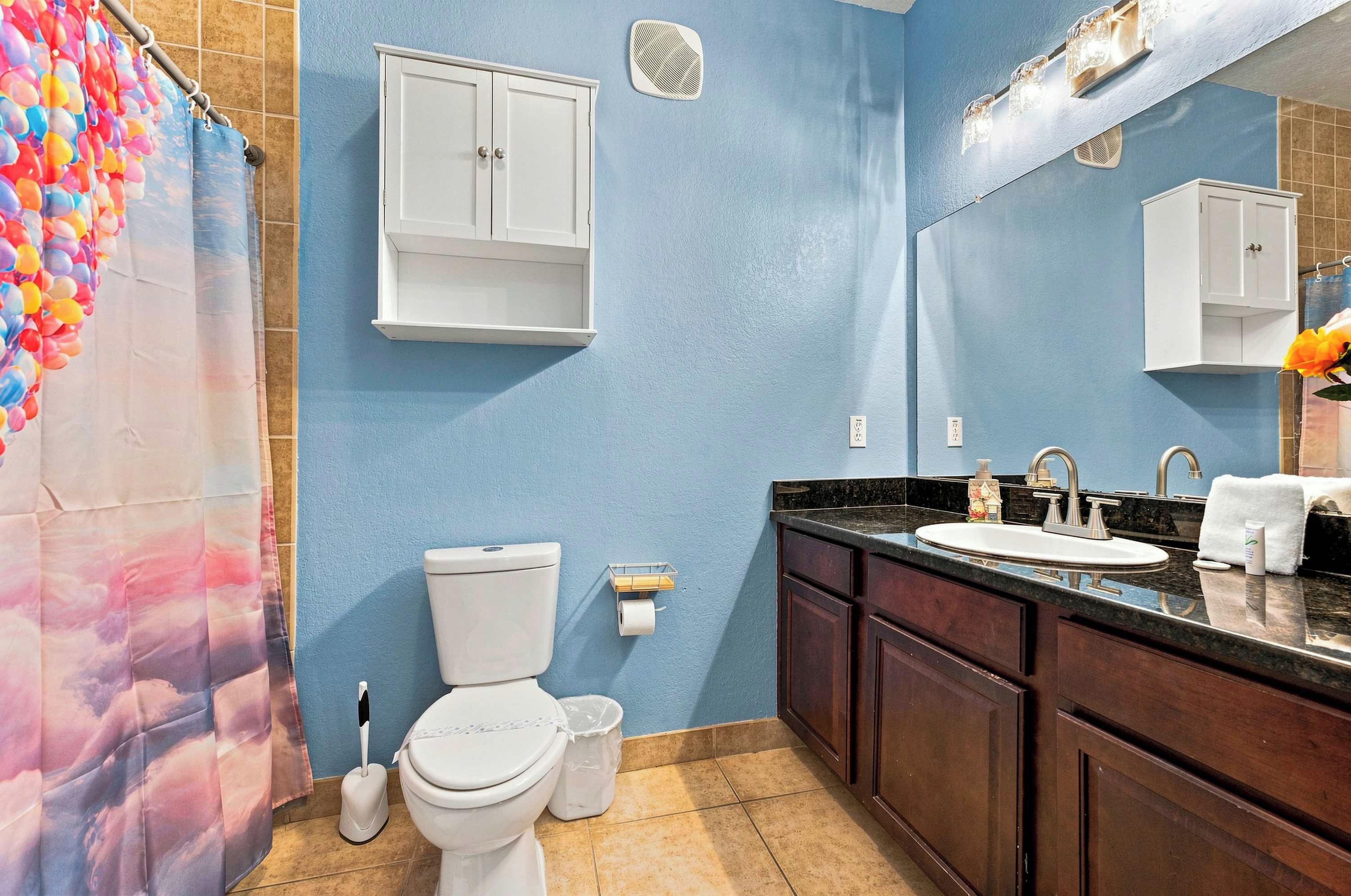 A bathroom with a toilet, sink, and cabinets.