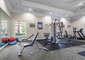 Ein Fitnessraum mit Trainingsgeräten, einem großen Fenster und einem Spiegel.