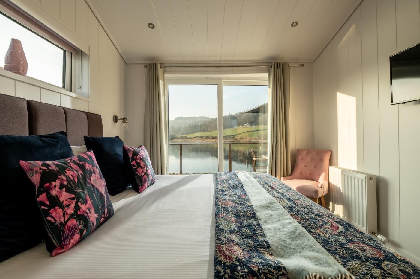 Ein Schlafzimmer mit einem großen Bett, Seeblick, einem Sessel und einer Heizung.