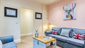 A living room with a blue sofa, a small wooden side table, and a decorative lamp. - 3 Bed in Buxton (oc-77955) (Tideswell)