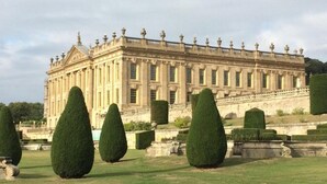 A large, classical building with symmetrical architecture, a formal garden with neatly trimmed hedges, and a clear sky. - 3 Bed in Buxton (oc-77955) (Tideswell)
