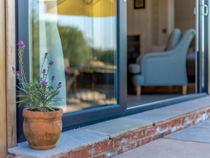 A potted plant with purple flowers on a ledge outside a building with a glass door. - 2 Bed in Ludlow (oc-78024) (Richards Castle)