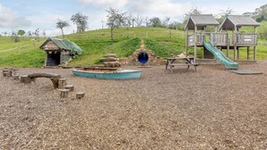 Ein Spielplatz mit Rutsche, Klettergerüsten und einem kleinen Gebäude.