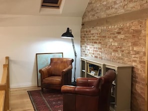 A room with a brick wall, a wooden chair, a floor lamp, and a bookshelf. - 6 Bed in Market Rasen (oc-78147) (East Barkwith)