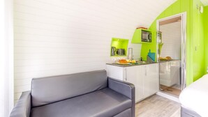 A compact kitchenette with a microwave, a coffee maker, and a sink. There is a grey sofa and a door leading to a bathroom. - 1 Bed in Lampeter (oc-78189) (Lampeter)