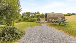 A rustic wooden structure with a gravel path leading to it, surrounded by greenery.