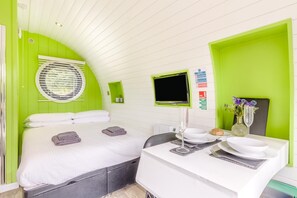 Una habitación con cama, escritorio, televisión y ventana con persianas.