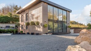 Ein modernes Gebäude mit flachem Dach, großen Fenstern und einer Schotterauffahrt.