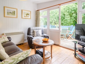 A living room with a sofa, a chair, a table with a bowl of fruit, a television, and a view of the outdoors through large windows. - 2 Bed in Parkham (oc-78252) (Parkham)