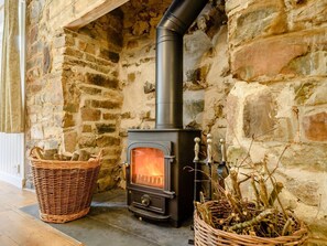 A stone fireplace with a wood-burning stove, wicker baskets, and a chimney. - 2 Bed in Parkham (oc-78252) (Parkham)
