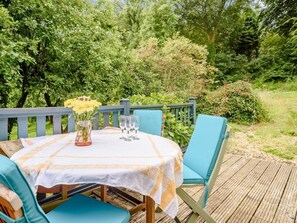 A table set outdoors with a white tablecloth and blue chairs, surrounded by greenery. - 2 Bed in Parkham (oc-78252) (Parkham)