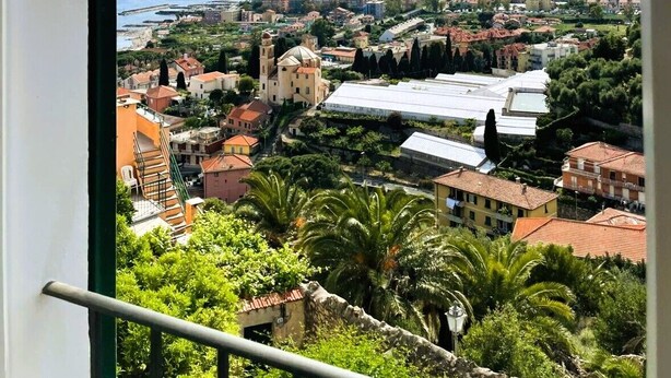 A coastal cityscape with a view of the sea, buildings, and hills.