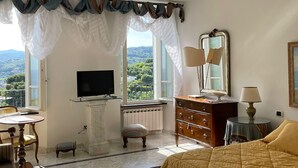A hotel room with a bed, a television, a dresser, a mirror, and a view of the outdoors.