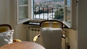 A room with a large window overlooking a cityscape, a radiator, and a table with chairs.