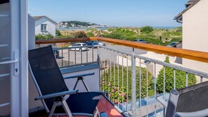 Ein Balkon mit Meerblick, einem Stuhl und einem Geländer.