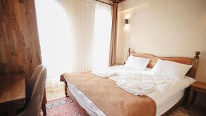 A bedroom with a wooden bed, a desk, and a patterned rug.
