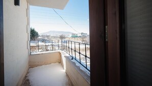 A balcony with a metal railing, a view of a snowy landscape, and a clear sky.