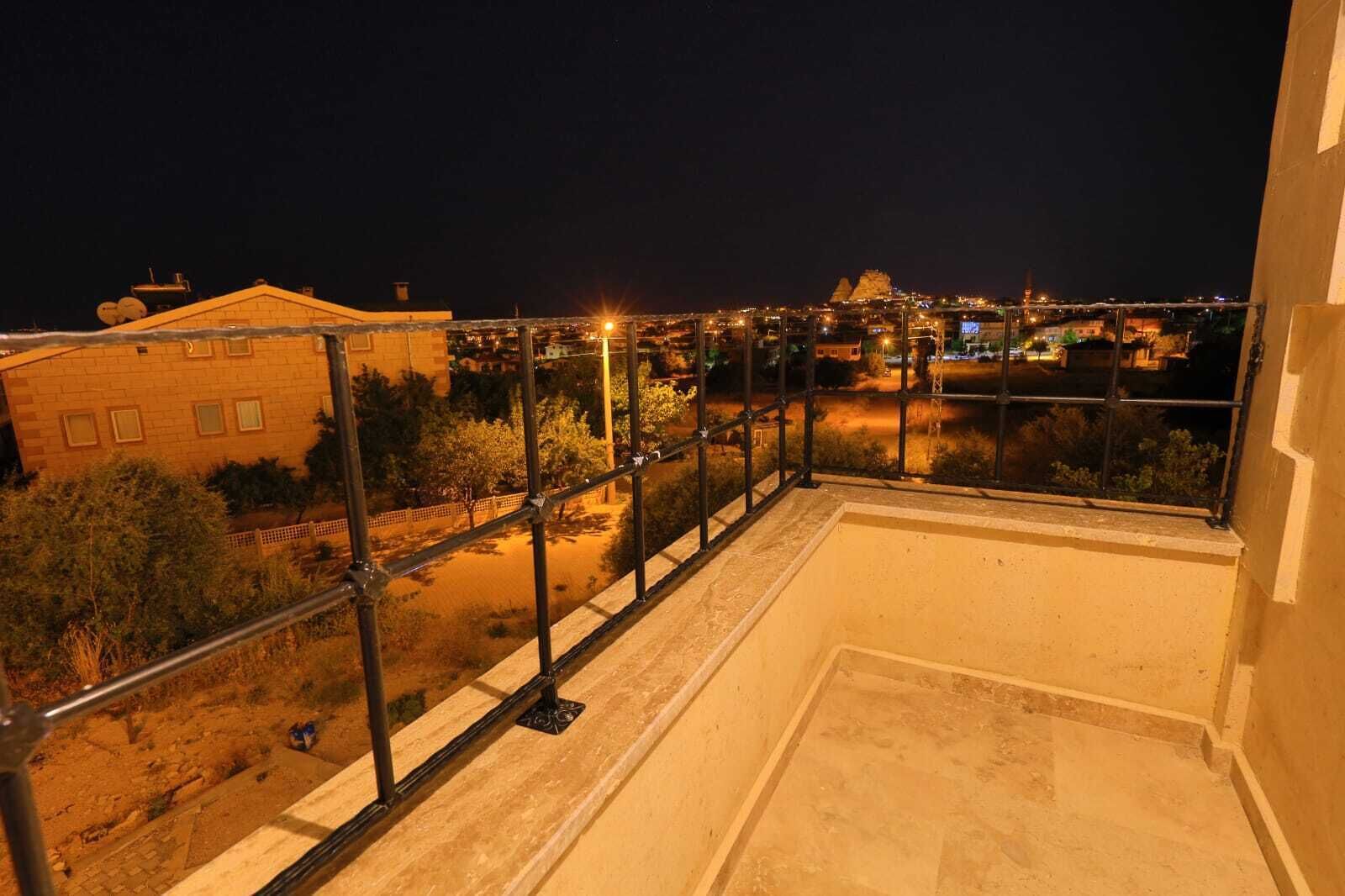 Un balcón con barandilla metálica que da a un paisaje urbano de noche.