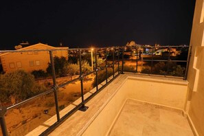 A balcony with a metal railing overlooking a cityscape at night. - Castle Stone House (Nevsehir)