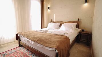 A neatly made bed with a brown blanket, a patterned rug, and two bedside tables with lamps.