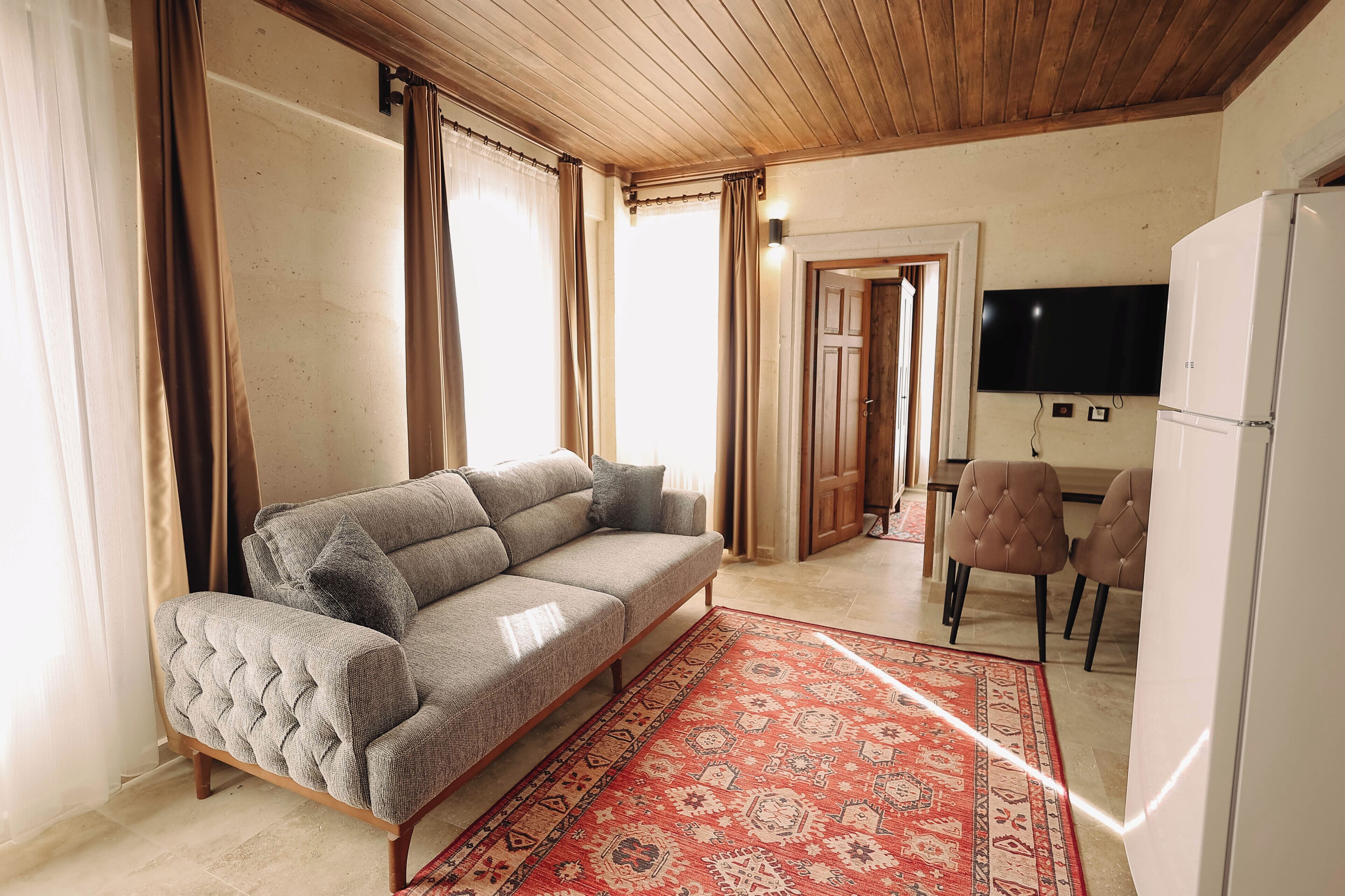 Ein Wohnzimmer mit einer Couch, einem Teppich mit Muster, einem Fernseher und einem Kühlschrank.