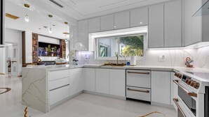 Una cocina moderna con armarios blancos, una isla de mármol y horno empotrado.