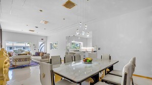 Un comedor moderno con una mesa de mármol, sillas blancas y un frutero.