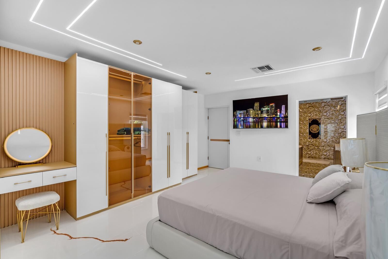 Een moderne slaapkamer met een bed, een kaptafel met spiegel, een kledingkast en een stadsgezicht kunstwerk aan de muur.