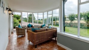 A sunroom with wicker furniture, large windows, and a view of the garden. - 3 Bed in Crieff (oc-78313) (Madderty)