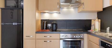 A modern kitchen with stainless steel appliances, wooden cabinets, and a built-in oven.