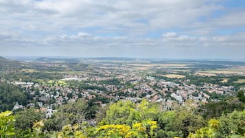 Weitläufige Aussicht auf eine Stadt mit einer Mischung aus Wohn- und Geschäftsgebäuden, umgeben von Grünflächen und Hügeln.