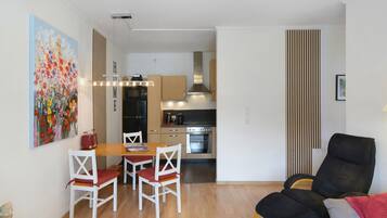 Um espaço compacto com área de refeições, cozinha compacta e canto de estar com uma cadeira preta.