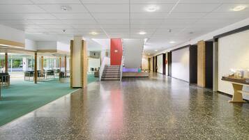 A spacious indoor area with a polished floor, a staircase, and a seating area with tables and chairs.