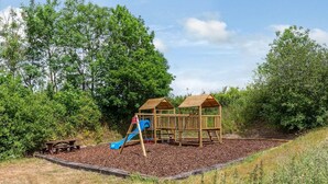 A playground with a slide and two wooden playhouses. - 3 Bed in Umberleigh (oc-78305) (Kings Nympton)