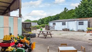 A rural outdoor area with a picnic table, chairs, and toy tractors. - 3 Bed in Umberleigh (oc-78305) (Kings Nympton)