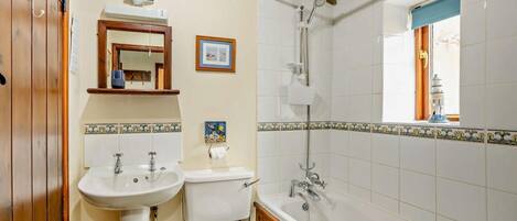 Une salle de bain avec un meuble-lavabo en bois, un lavabo, des toilettes et une baignoire.
