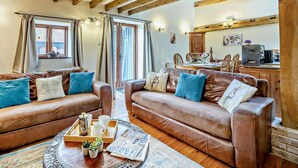 Una sala de estar acogedora con sofás de cuero, una mesita de centro con revistas y un techo de madera.
