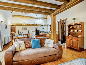 A cozy living room with a leather sofa, wooden beams, a dining area, and a kitchen with wooden cabinets. - 2 Bed in King's Lynn (oc-kt125) (Tattersett)