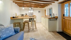 Una cocina con vigas de madera, una isla central, taburetes de bar, un lavamanos y una ventana con vistas.