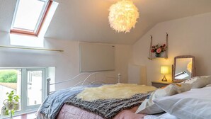 A bedroom with a bed, a hanging light fixture, a window, and a bedside table with a lamp. - 2 Bed in Umberleigh (oc-78303) (Kings Nympton)
