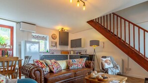A cozy living room with a brown leather sofa, a wooden coffee table, and a staircase. - 2 Bed in Umberleigh (oc-78303) (Kings Nympton)