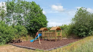 A playground with two wooden playhouses and a blue slide. - 2 Bed in Umberleigh (oc-78303) (Kings Nympton)