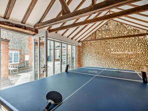Ein Tischtennis-Tisch in einem Raum mit Steinwand und Holzbalken.
