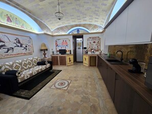 A spacious living area with a sofa, a coffee table, a kitchen with a sink and counter, and a decorative ceiling. - The Etrurian Rapsody (Rome)