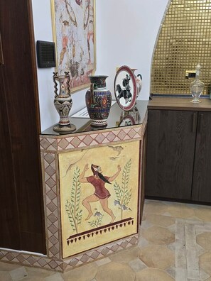 Une pièce dotée d’un sol carrelé, d’un mur décoratif orné d’une mosaïque et d’un meuble en bois dont le dessus est en verre.